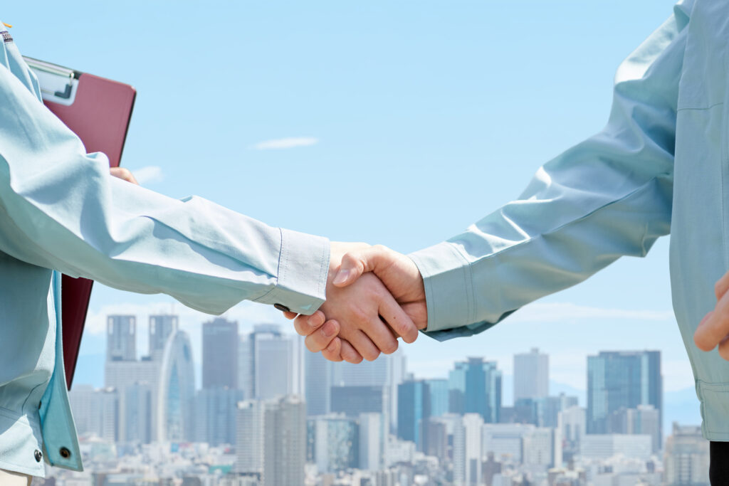 Two business professionals shaking hands in front of a downtown skyline